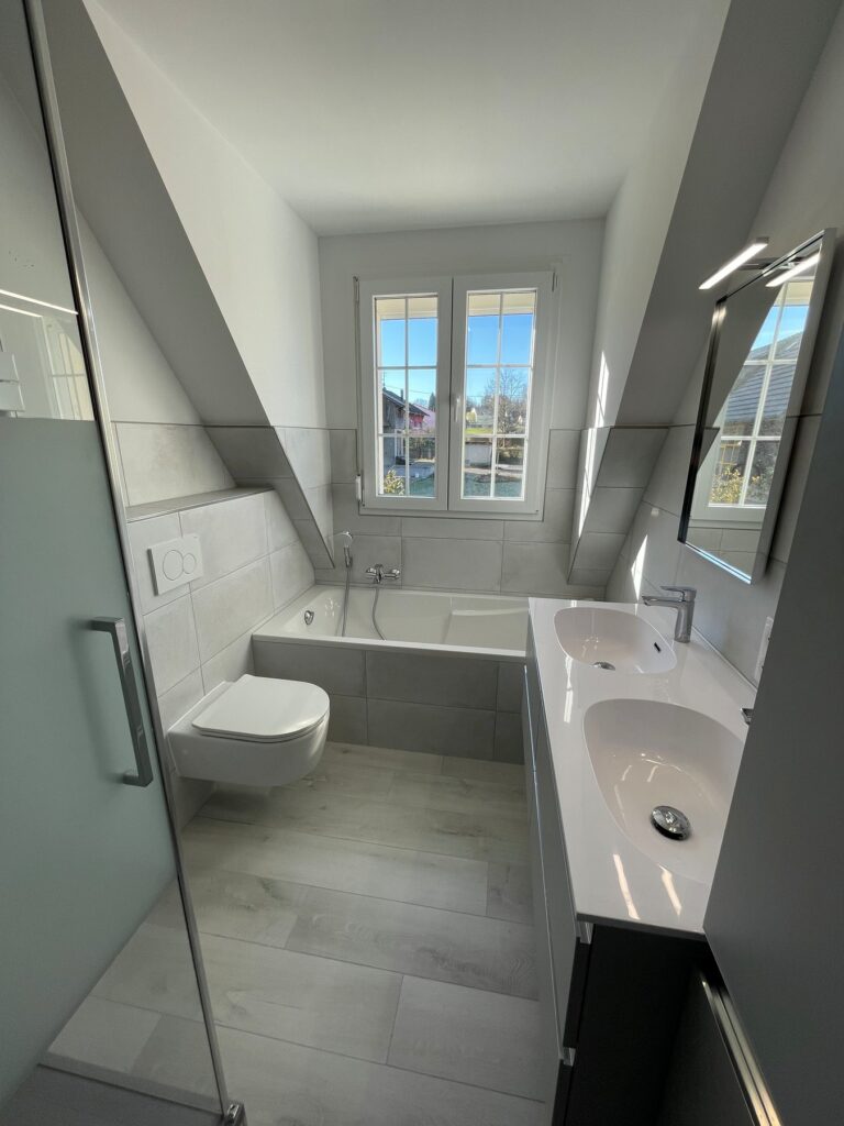 Après rénovation : baignoire, WC suspendu et vasque dans un espace clair