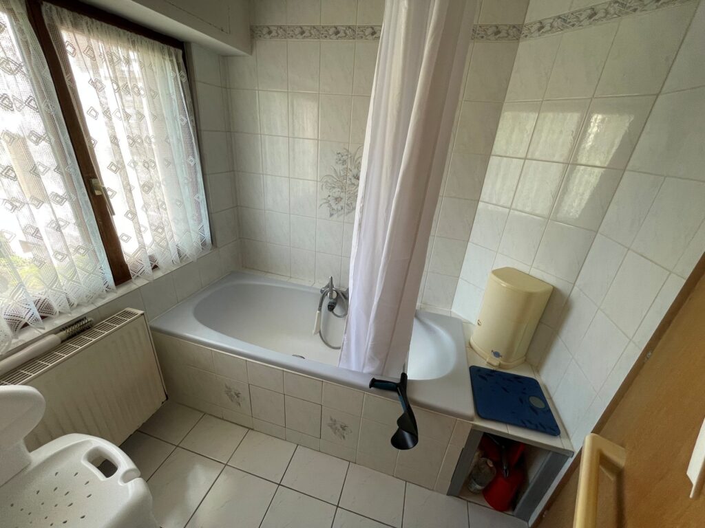 Avant rénovation : baignoire avec rideau de douche et faïence blanche