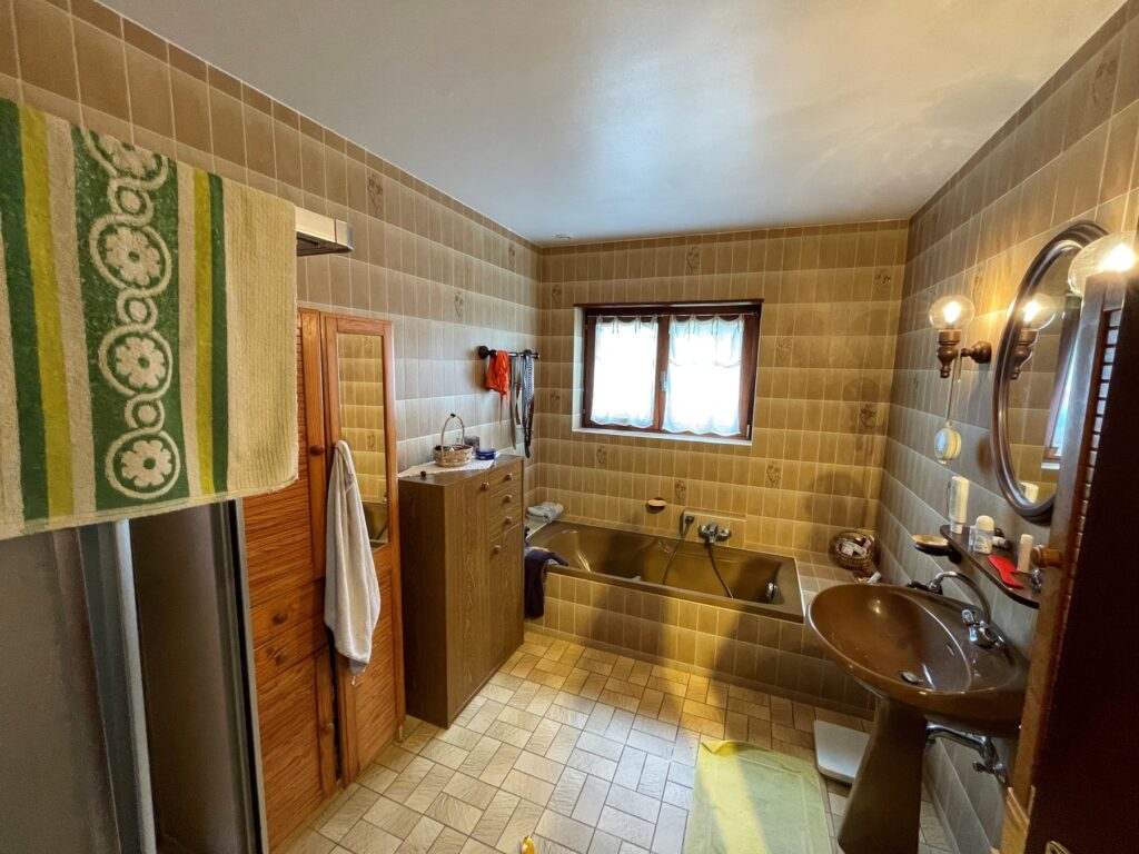 Avant rénovation : salle de bains d’origine, carrelage beige et mobilier bois